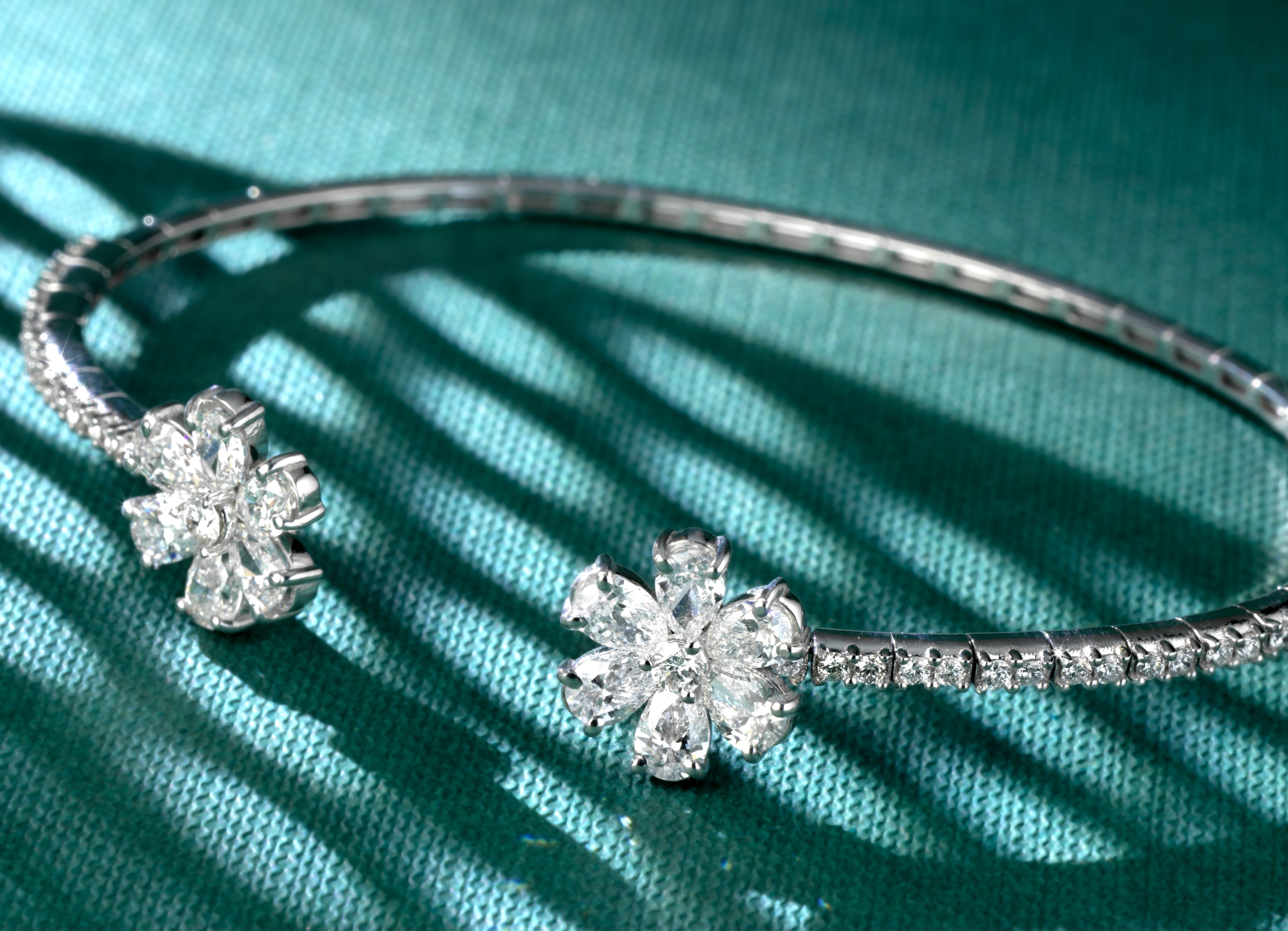 BRACCIALE IN ORO BIANCO APERTO CON DUE FIORI DI DIAMANTI A GOCCIA E DIAMANTI