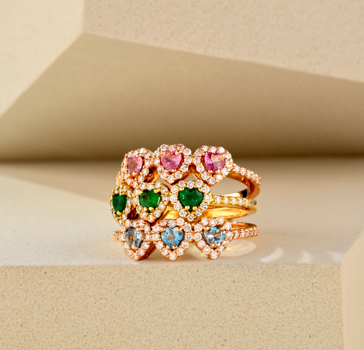 ANELLO A TRE  CON DIAMANTI E CUORI CENTRALI DI SMERALDO IN ORO GIALLO